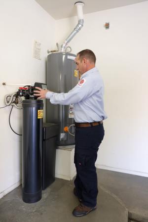 John’s Heating, Cooling, and Plumbing plumber working on a water heater repair in Chandler.