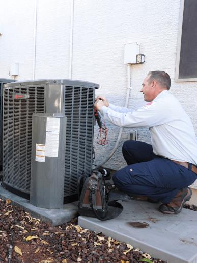A John’s technician inspecting an air conditioner in Mesa